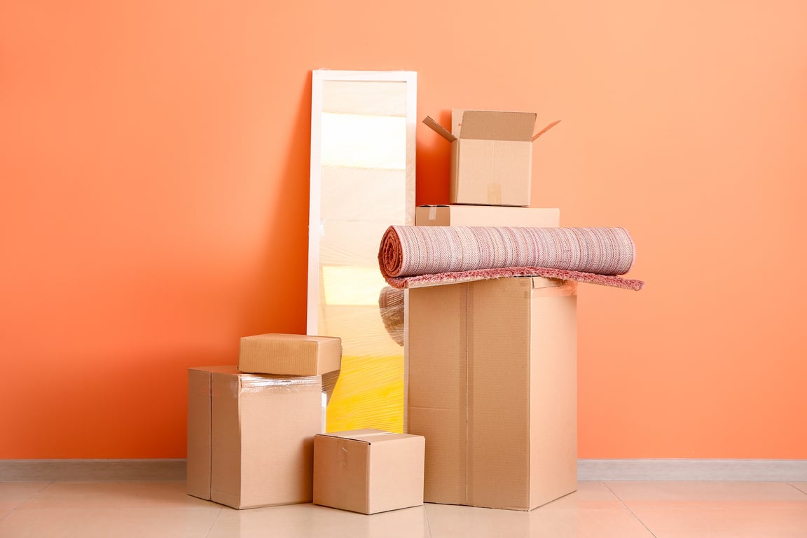 Cardboard Boxes with Belongings Prepared for Moving into New House near Color Wall